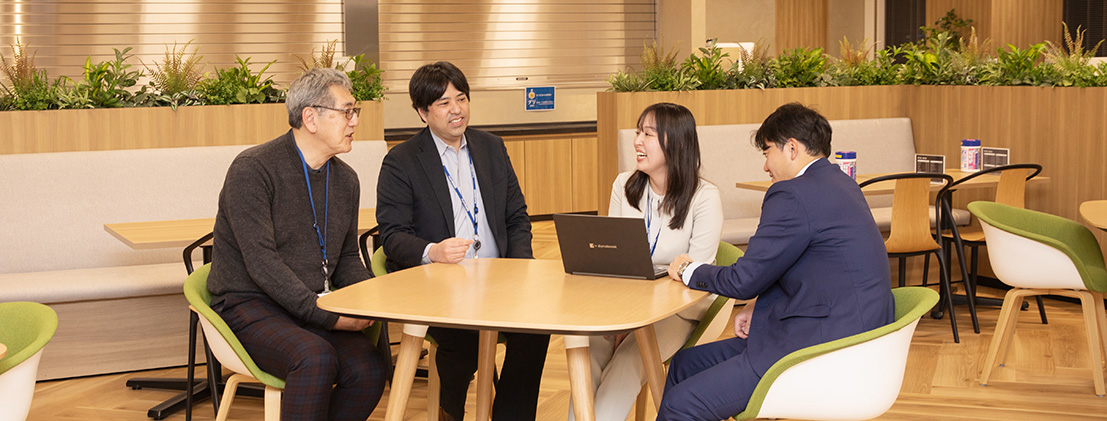 チームの方達と机を囲んで会話をする 領域マネジメント部 感染症領域企画室 M.Kurosawa